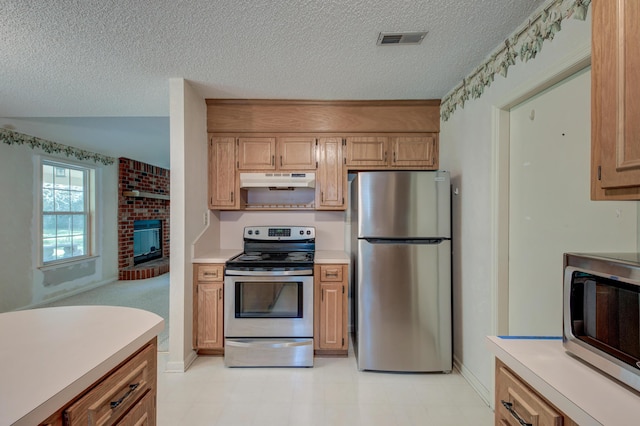 441 Compton Dr, Moncks Corner, SC 29461 - kitchen featuring appliances with stainless steel finishes, under cabinet range hood, light countertops, a textured ceiling, and a fireplace