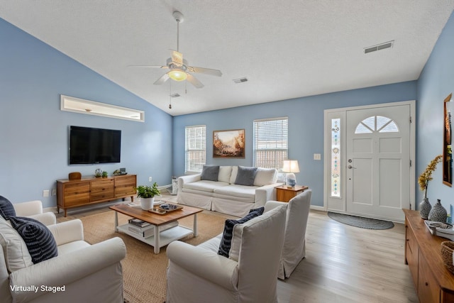 living area with a textured ceiling, light wood-style flooring, visible vents, and ceiling fan