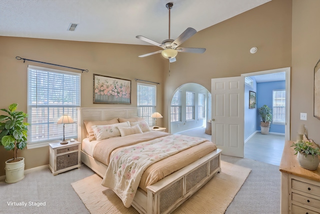 bedroom featuring visible vents, light colored carpet, high vaulted ceiling, and baseboards