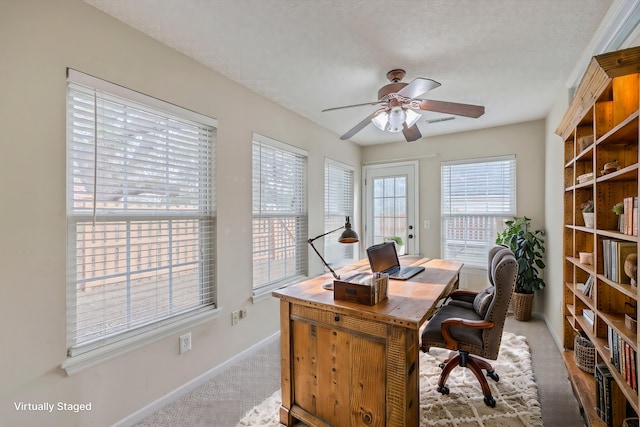 office featuring a textured ceiling, baseboards, a ceiling fan, and carpet floors