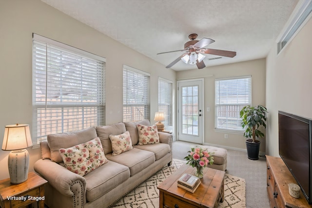 carpeted living room featuring baseboards, a textured ceiling, and ceiling fan