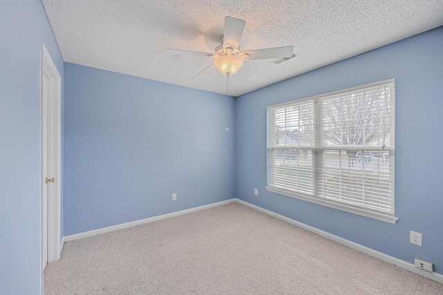 carpeted empty room featuring visible vents, ceiling fan, a textured ceiling, and baseboards