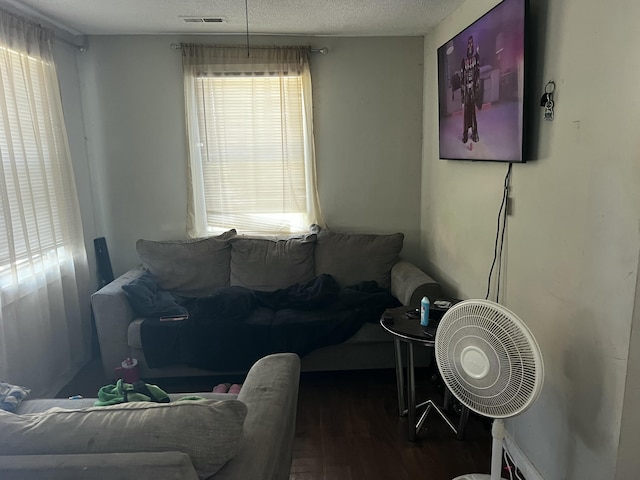 living room featuring visible vents, a textured ceiling, and wood finished floors