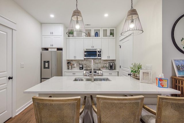 kitchen with tasteful backsplash, appliances with stainless steel finishes, pendant lighting, and white cabinetry