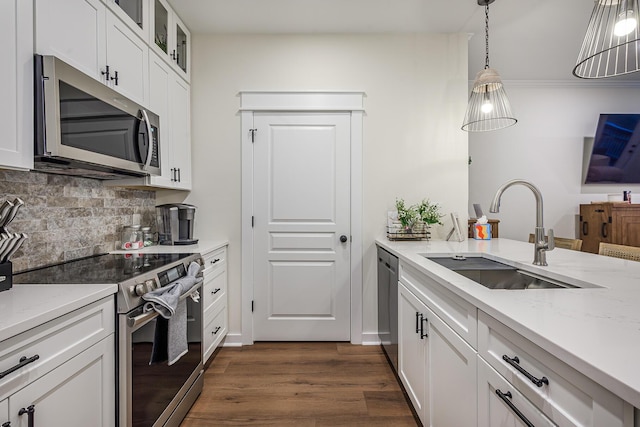 kitchen with appliances with stainless steel finishes, white cabinets, decorative light fixtures, and sink