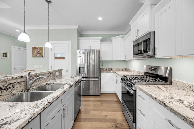 kitchen with stainless steel appliances, sink, pendant lighting, light hardwood / wood-style flooring, and white cabinets