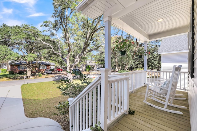 wooden terrace with a lawn and a porch