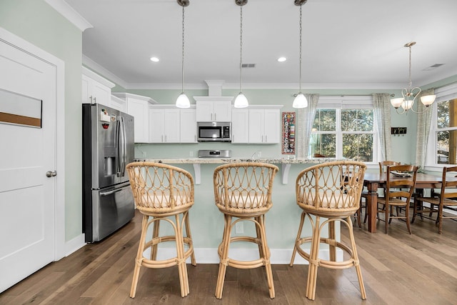 kitchen featuring hardwood / wood-style floors, crown molding, white cabinets, and stainless steel appliances