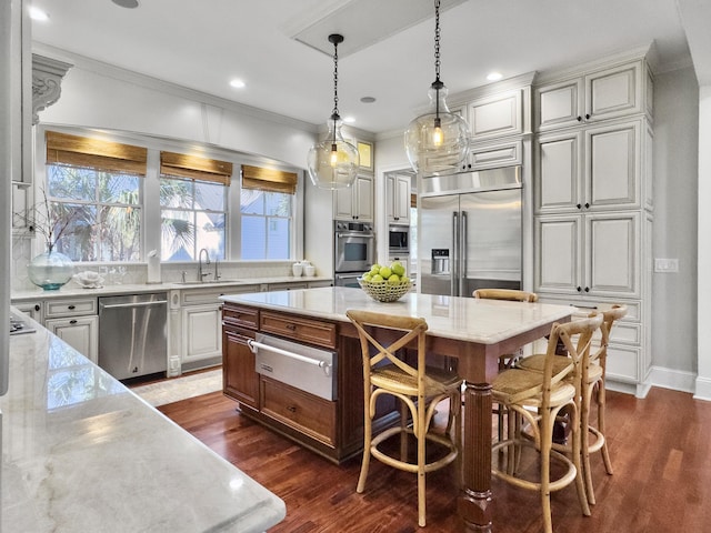 kitchen featuring light stone countertops, a kitchen bar, built in appliances, a center island, and dark hardwood / wood-style floors