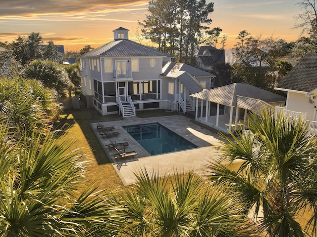 back house at dusk featuring a patio and a sunroom