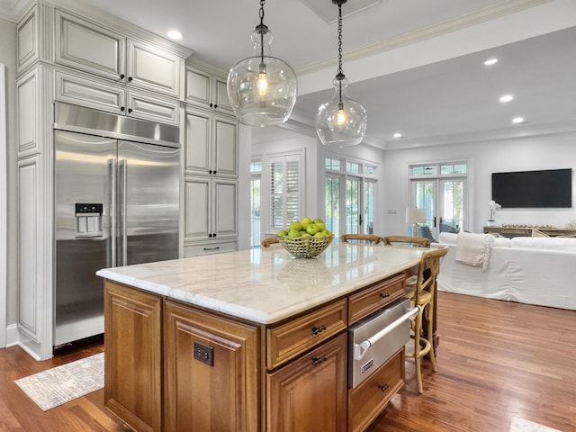 kitchen with french doors, a center island, dark wood-type flooring, light stone counters, and stainless steel built in refrigerator