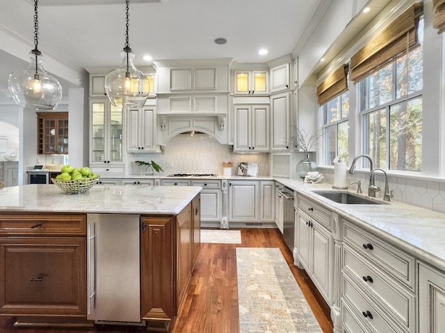 kitchen with decorative backsplash, sink, pendant lighting, white cabinets, and a kitchen island