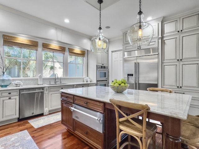 kitchen with hanging light fixtures, sink, a breakfast bar area, a kitchen island, and stainless steel appliances