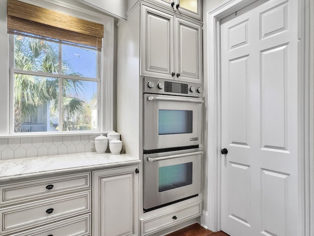 kitchen featuring light stone countertops and stainless steel double oven