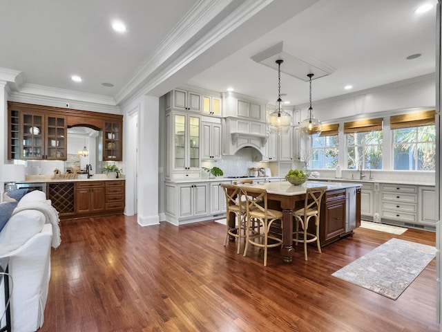 kitchen featuring a breakfast bar, decorative backsplash, decorative light fixtures, a kitchen island, and dark hardwood / wood-style flooring