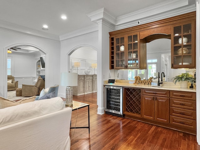 bar with dark hardwood / wood-style flooring, ornamental molding, and beverage cooler