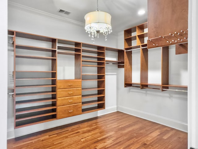 walk in closet with a notable chandelier and wood-type flooring