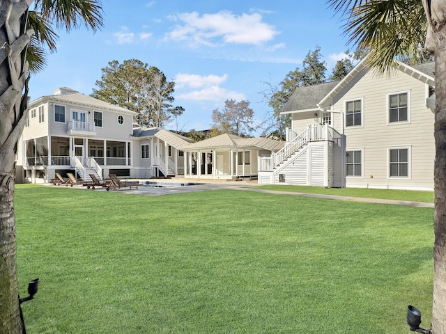 back of house with a sunroom, a patio area, and a lawn