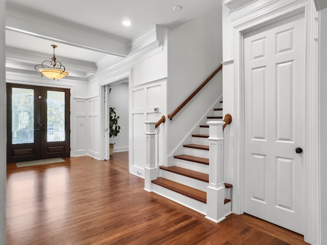 entrance foyer with beam ceiling, dark hardwood / wood-style flooring, ornamental molding, and french doors