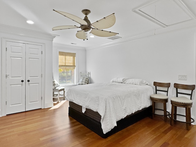 bedroom with hardwood / wood-style floors, ceiling fan, ornamental molding, and a closet