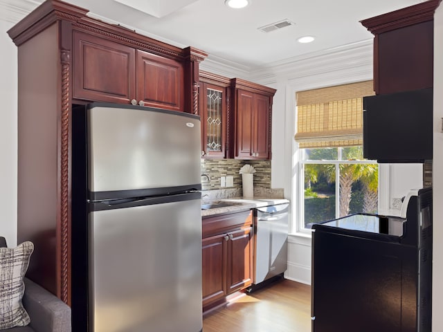 kitchen featuring sink, stainless steel appliances, backsplash, light hardwood / wood-style floors, and ornamental molding