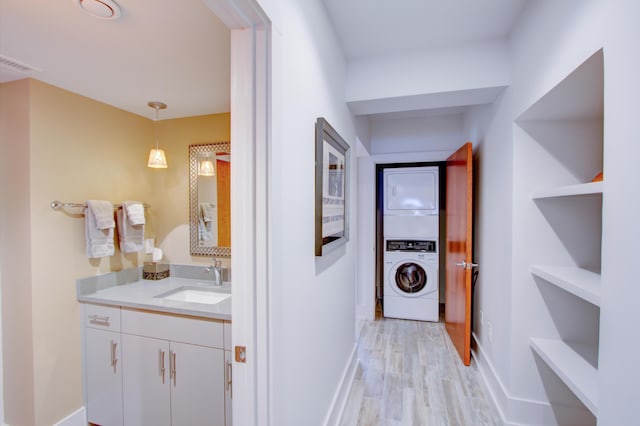 hallway with light hardwood / wood-style floors, stacked washer and clothes dryer, and sink