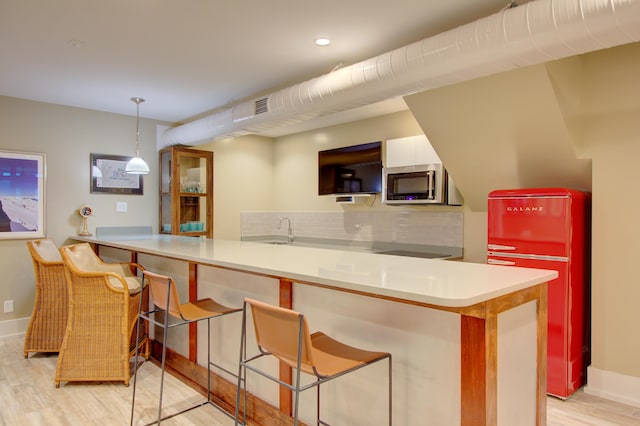 kitchen featuring kitchen peninsula, a kitchen breakfast bar, tasteful backsplash, pendant lighting, and white cabinetry