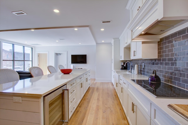 kitchen featuring decorative backsplash, a kitchen island, white cabinetry, and wine cooler