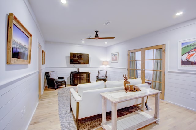 living room with ceiling fan, crown molding, light hardwood / wood-style floors, and french doors