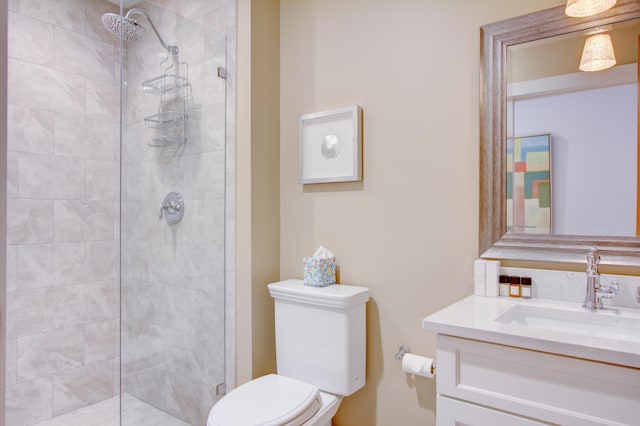 bathroom with tiled shower, vanity, and toilet