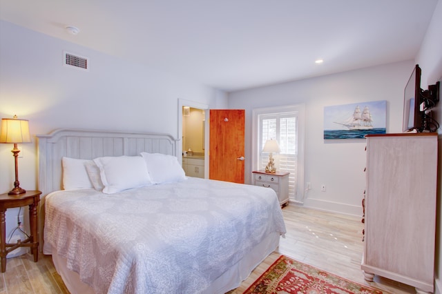 bedroom with light hardwood / wood-style floors and ensuite bath