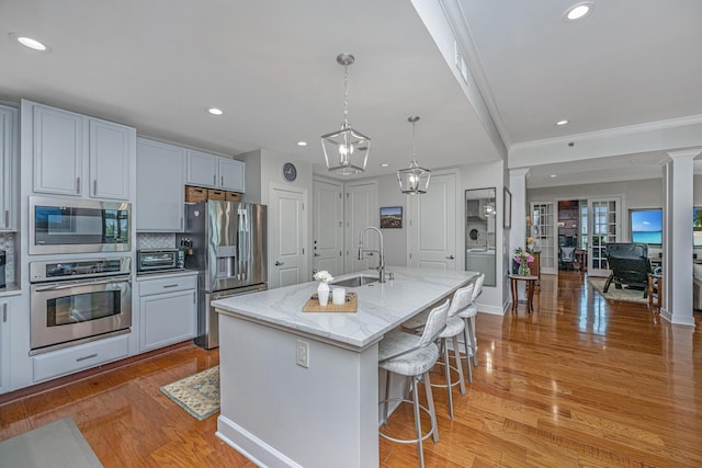 125 Pier View St Unit 408, Charleston, SC 29492 - kitchen with stainless steel appliances, crown molding, light stone counters, a breakfast bar area, and hanging light fixtures