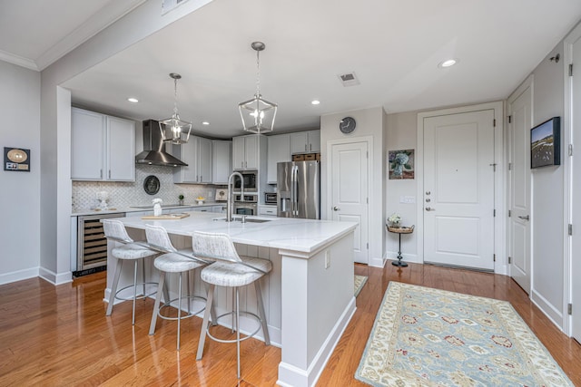 125 Pier View St Unit 408, Charleston, SC 29492 - kitchen with stainless steel appliances, beverage cooler, wall chimney exhaust hood, backsplash, and a kitchen island with sink
