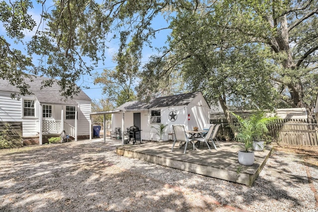 rear view of house with outdoor dining space, fence, a wooden deck, and an outdoor structure