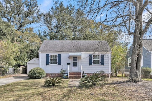 view of front facade with an outbuilding, a shingled roof, fence, crawl space, and a front yard