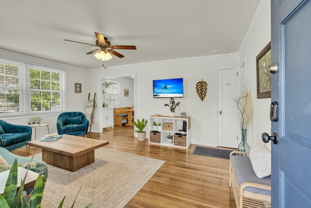 living room with light wood finished floors, ceiling fan, ornamental molding, and baseboards