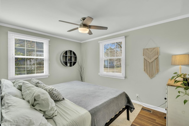 bedroom featuring multiple windows, crown molding, visible vents, and wood finished floors