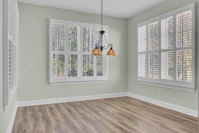 unfurnished dining area with hardwood / wood-style flooring and an inviting chandelier