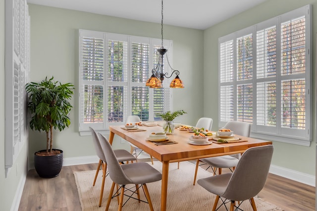 dining area with wood-type flooring and an inviting chandelier