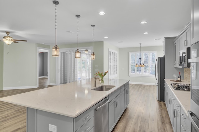 kitchen with gray cabinetry, stainless steel appliances, a spacious island, sink, and pendant lighting