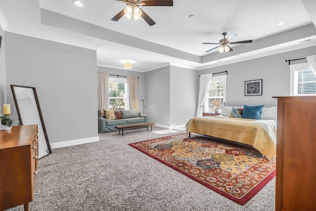 carpeted bedroom featuring crown molding, ceiling fan, and a raised ceiling