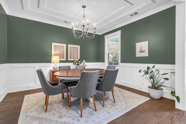 dining area with ornamental molding, dark wood-type flooring, a chandelier, and a tray ceiling