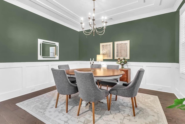 dining room featuring crown molding, wood-type flooring, a raised ceiling, and a notable chandelier