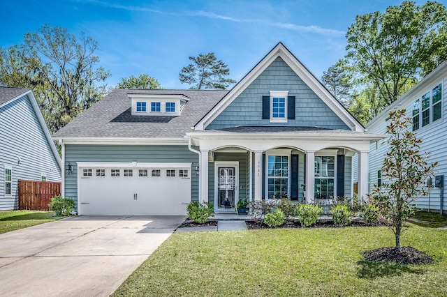 view of front of home featuring driveway, a shingled roof, an attached garage, covered porch, and a front yard