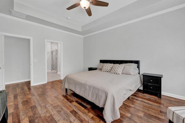 bedroom featuring a raised ceiling, visible vents, baseboards, and hardwood / wood-style flooring