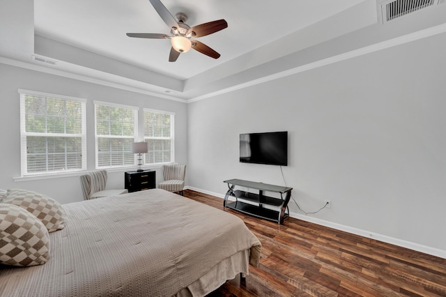 bedroom featuring baseboards, visible vents, a tray ceiling, and wood finished floors