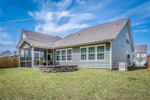 rear view of property featuring a sunroom, a shingled roof, fence, and a lawn