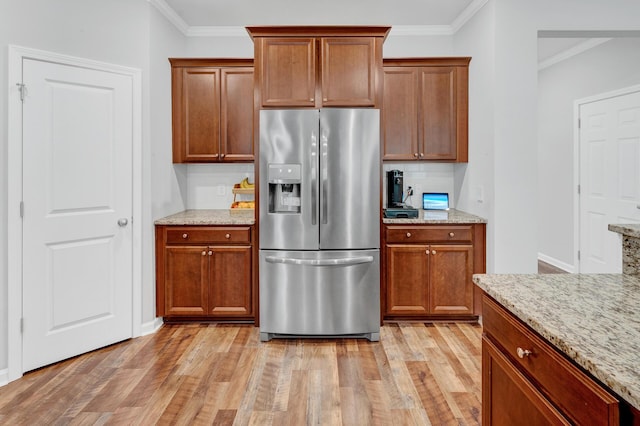 kitchen with light wood-style floors, backsplash, stainless steel fridge, and crown molding