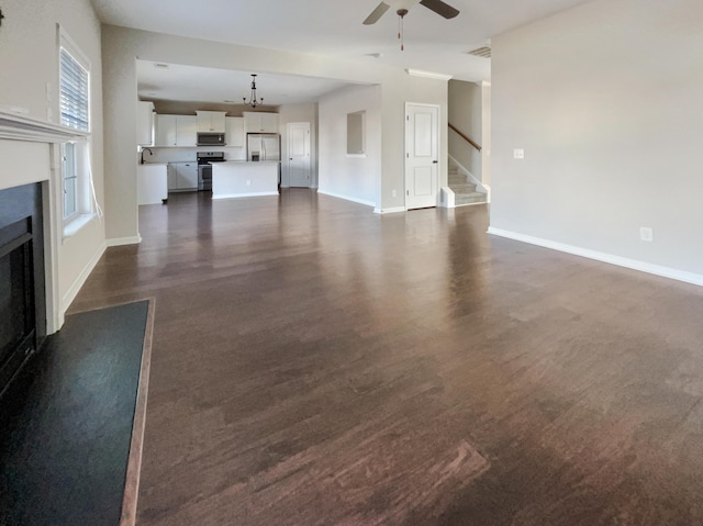 unfurnished living room featuring ceiling fan and dark hardwood / wood-style floors