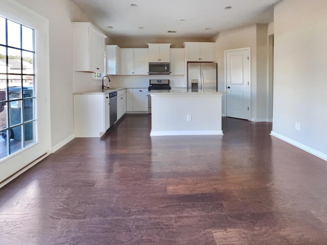 kitchen featuring sink, appliances with stainless steel finishes, dark hardwood / wood-style floors, a center island, and white cabinets